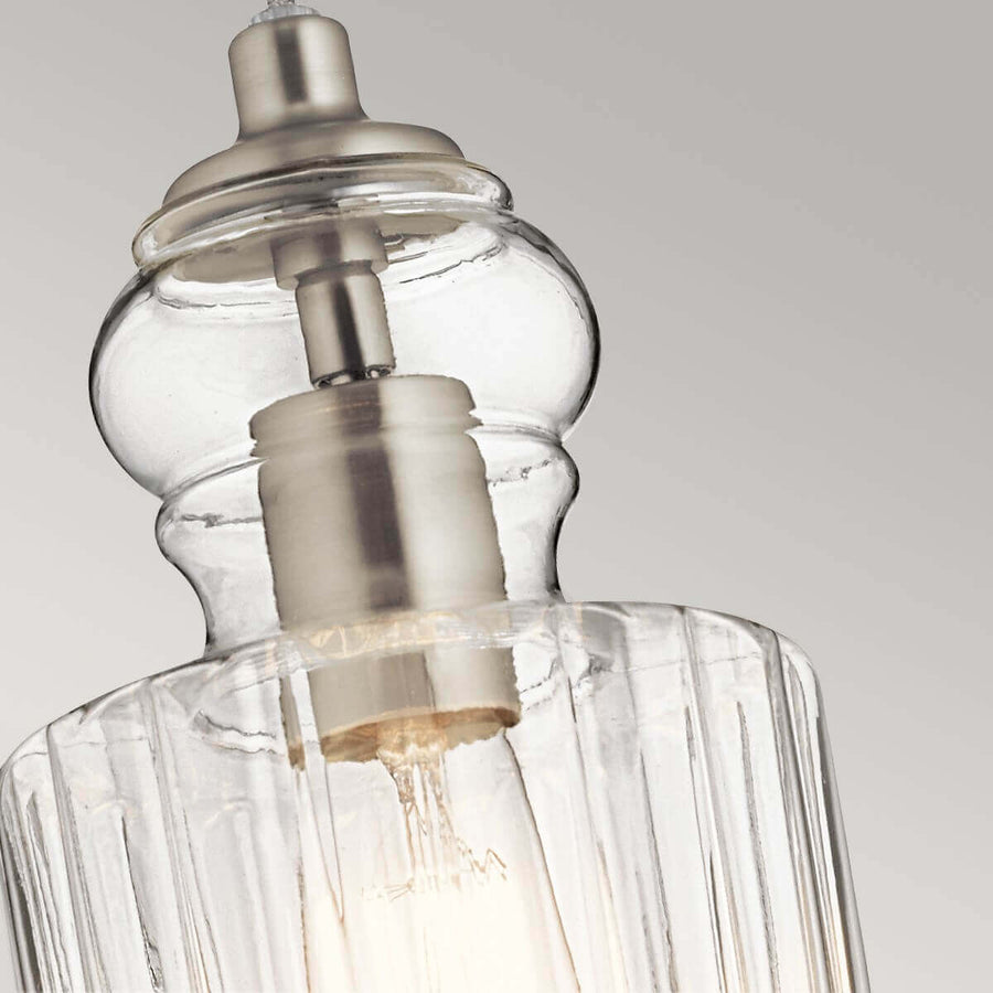 Gros plan sur la douille métallique et le verre strié transparent du luminaire.