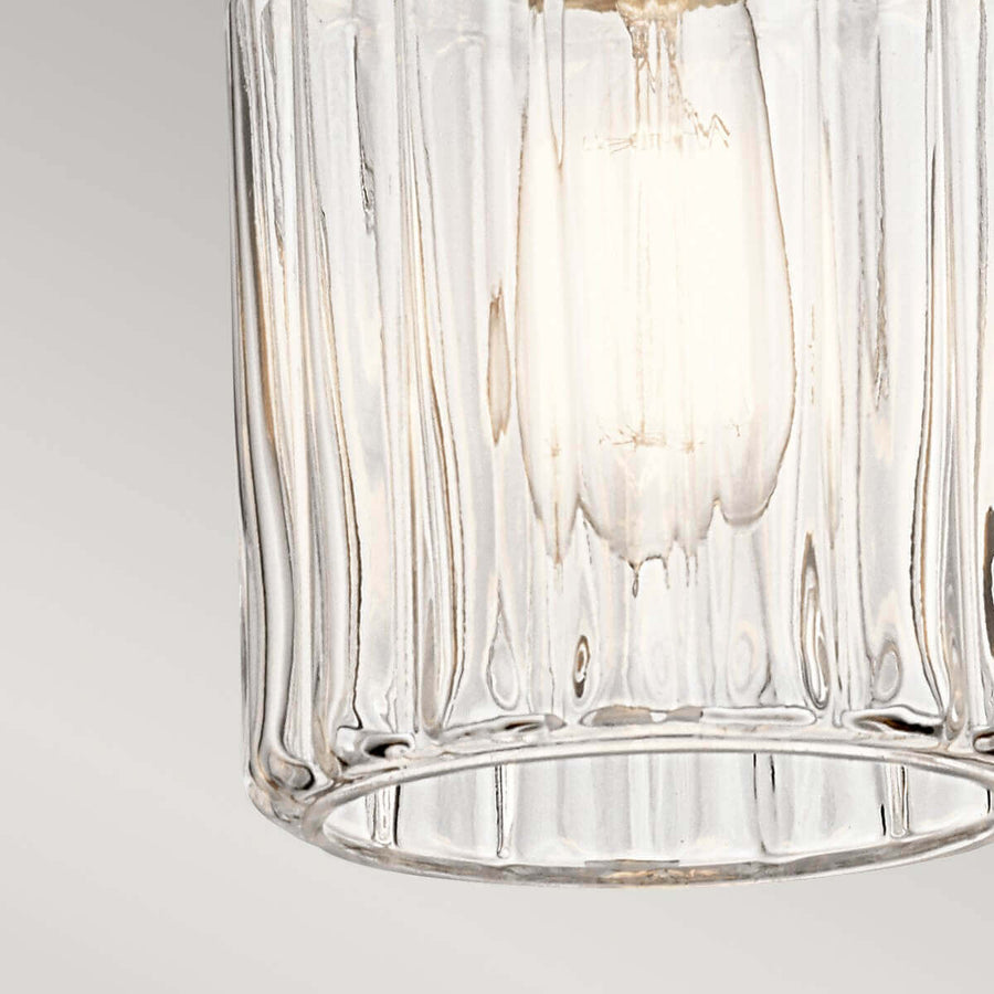 Détail du bas du verre cylindrique strié, ampoule allumée visible à l'intérieur.