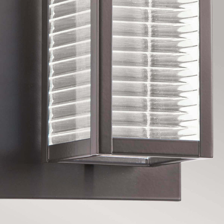 Détail du bas de l'applique en contre-plongée, cadre bronze et verre rainuré
