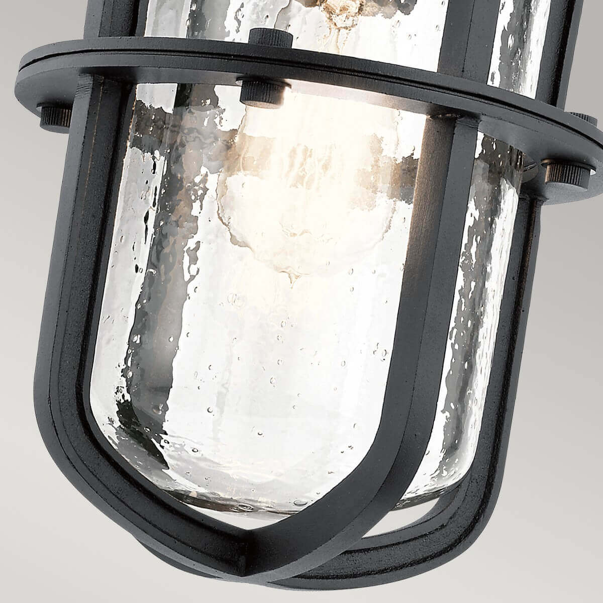 Bas de l'applique éclairé, cage métallique et verre bullé transparent