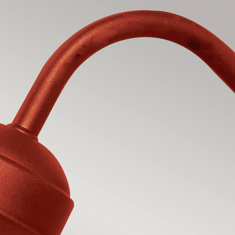Plan serré sur le bras cintré en métal rouge sur fond blanc neutre