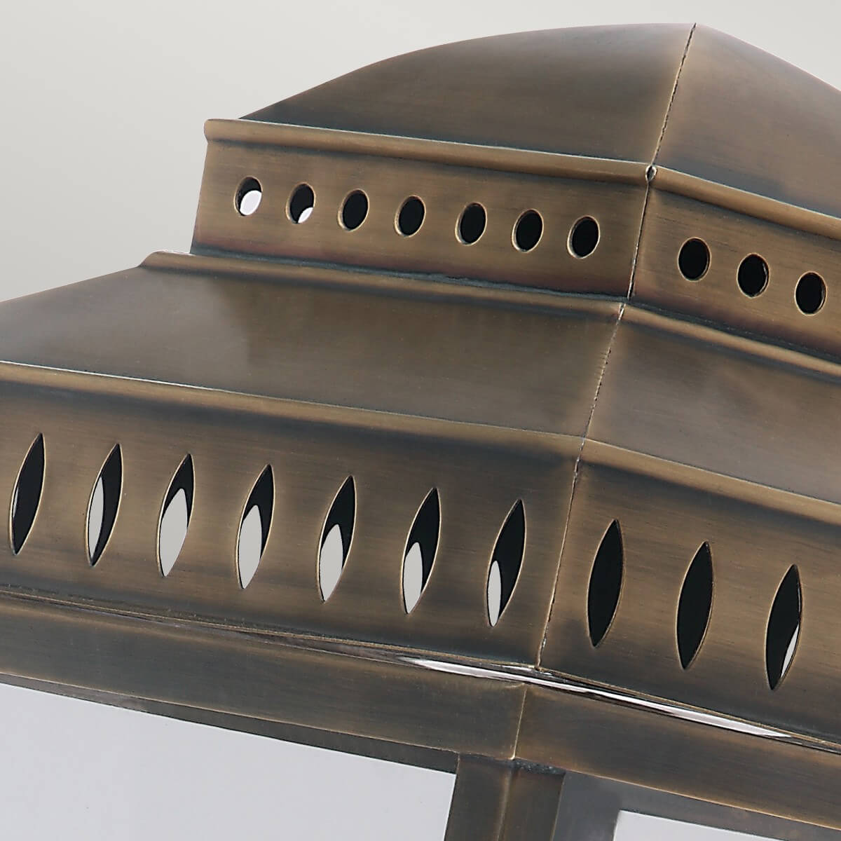 Détail du chapeau bombé ajouré et de la finition laiton vieilli du luminaire.