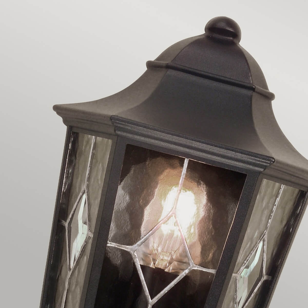 Détail du chapeau bombé noir avec finial et bordure moulurée du luminaire.