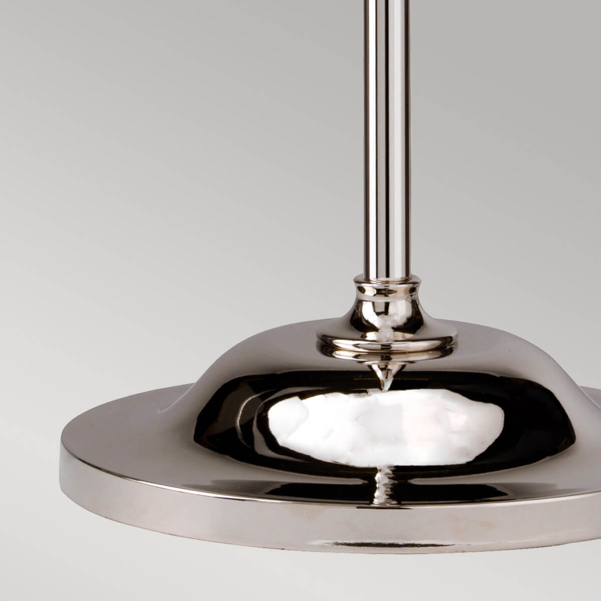 Détail de la base ronde bombée et du pied vertical en nickel poli.