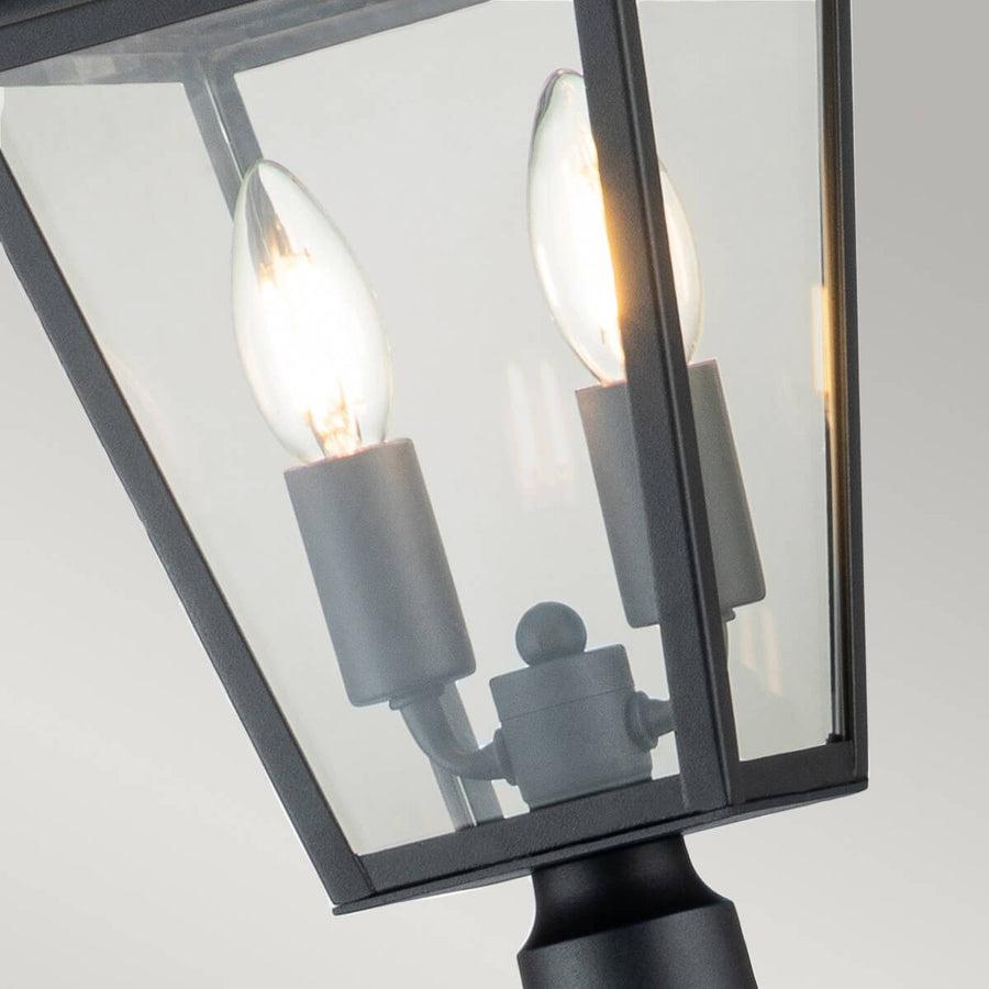 Gros plan sur les deux ampoules à filament allumées à l'intérieur de la lanterne vitrée.