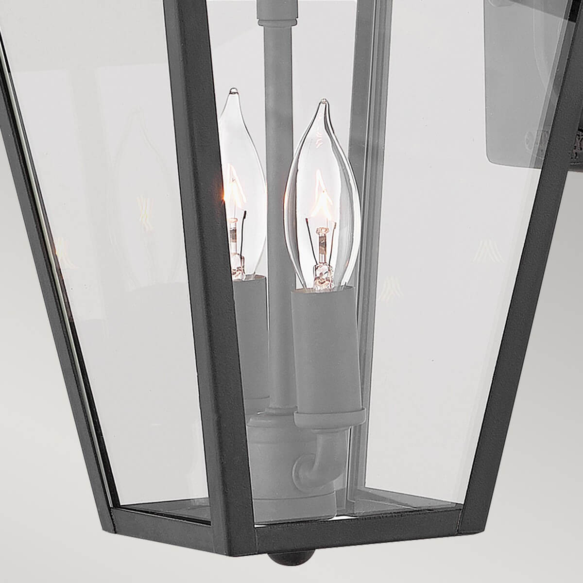 Vue rapprochée des deux ampoules flamme allumées derrière le verre transparent.