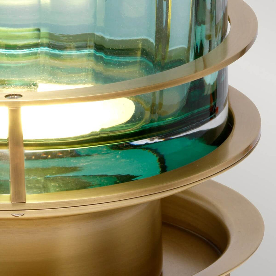Vue rapprochée de la base en laiton et du verre éclairé, montrant l'ampoule à l'intérieur.