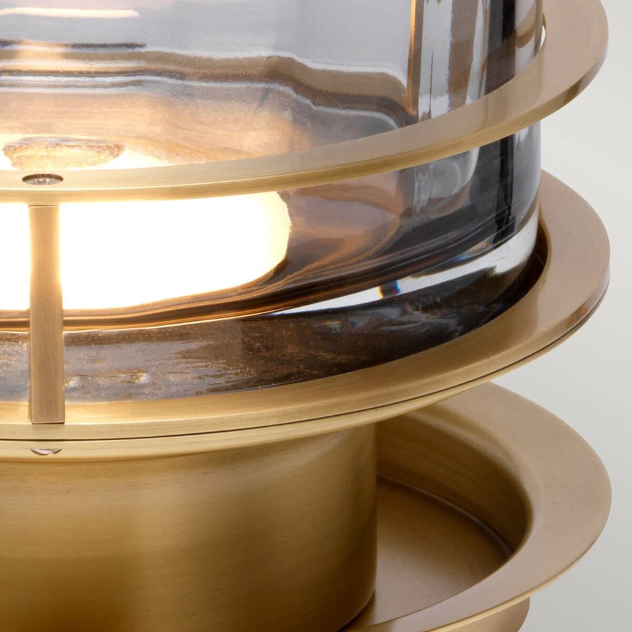 Détail du socle en laiton et de l'ampoule allumée à travers le verre