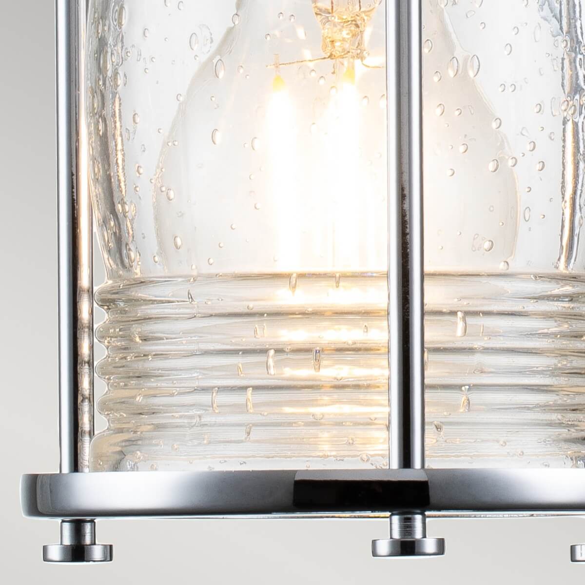 Gros plan de l'ampoule allumée derrière le verre bullé transparent