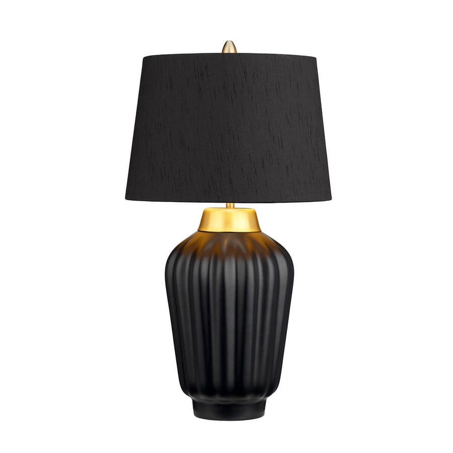 Même lampe allumée, lumière chaude soulignant les cannelures et le col laiton