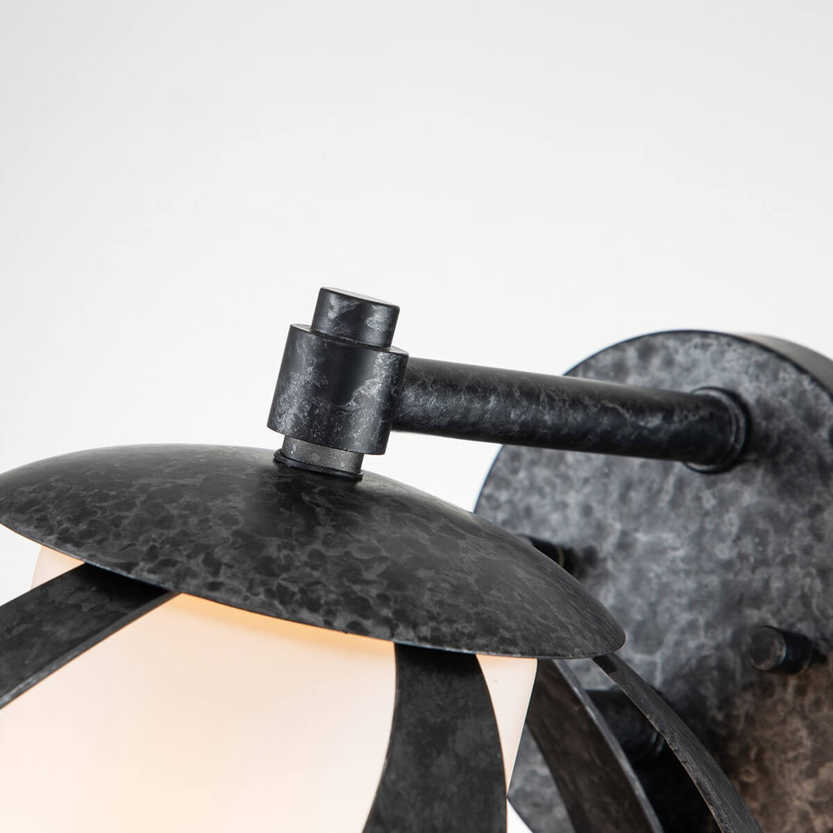 Détail du bras articulé et de la platine ronde au fini zinc martelé sombre