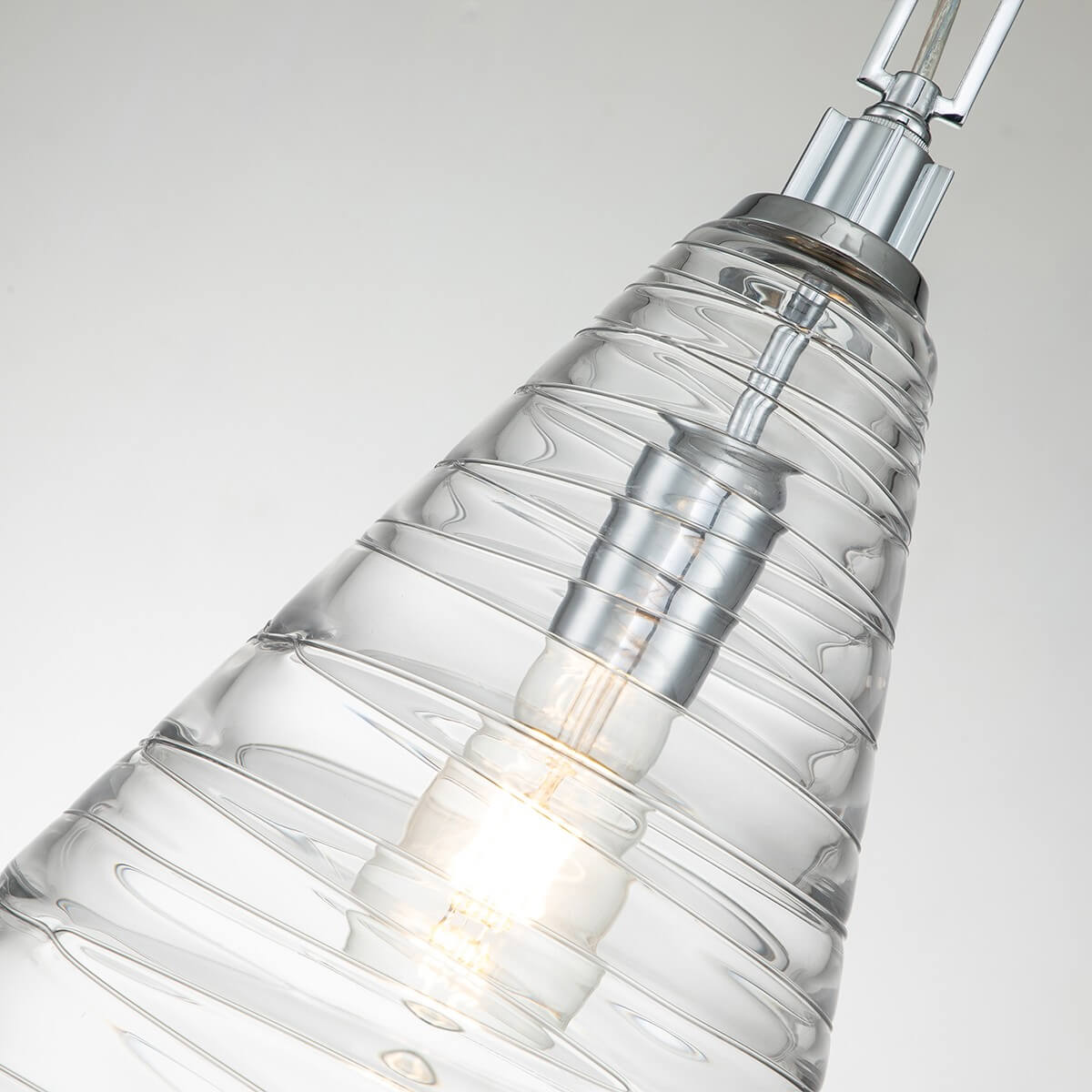 Vue rapprochée du cône en verre, douille chromée et ampoule allumée à l'intérieur.