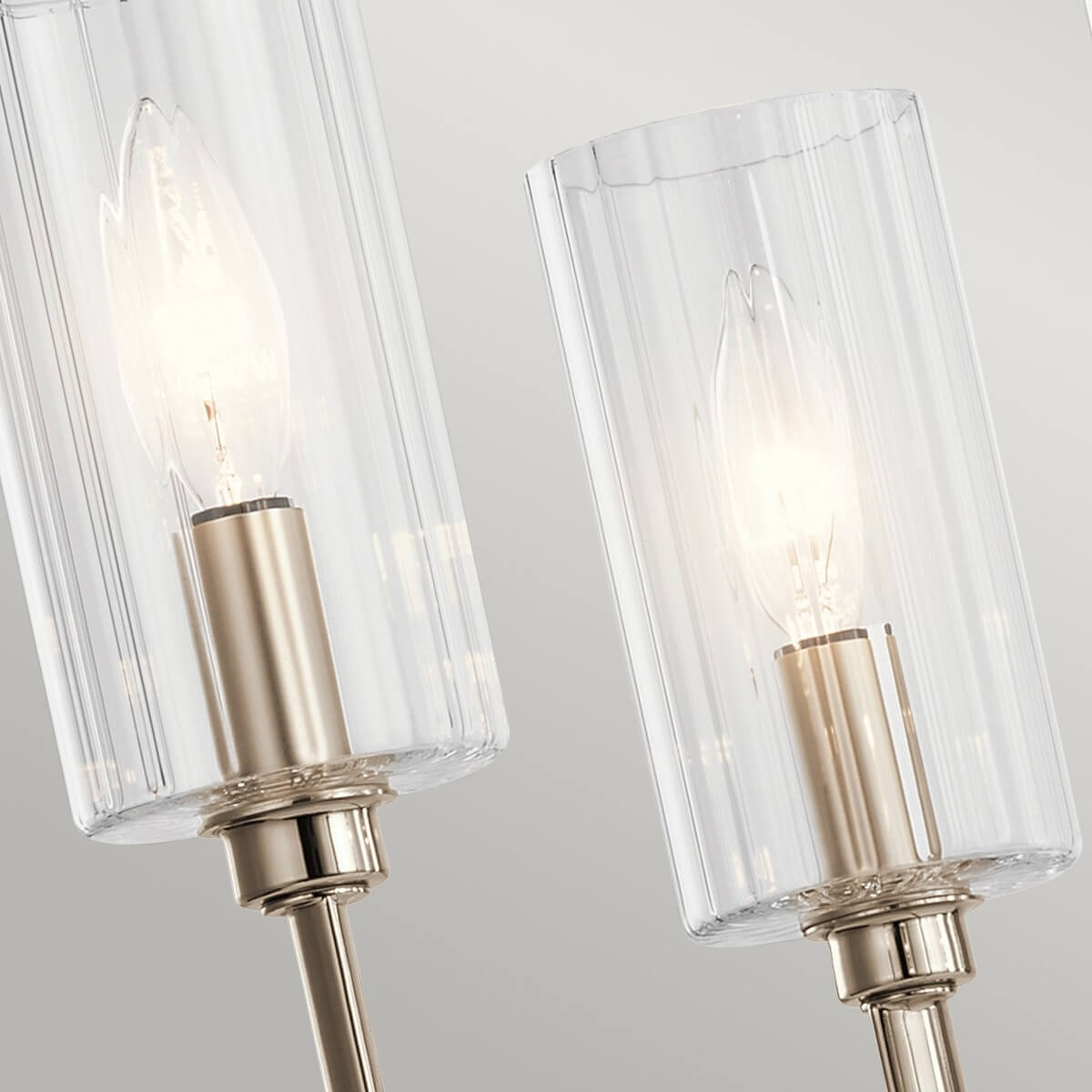 Détail rapproché de deux diffuseurs cylindriques en verre strié et ampoules allumées