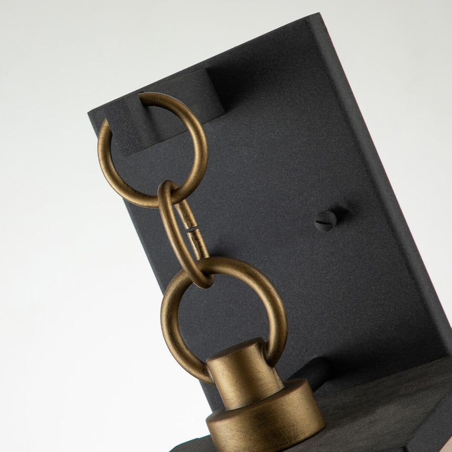 Détail de la chaîne dorée et de la platine de fixation murale noire