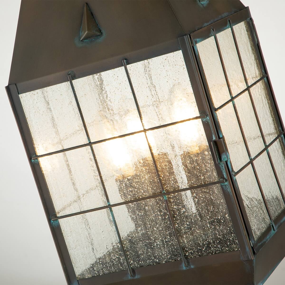 Détail du verre grêlé et de la grille métallique, trois ampoules allumées à l'intérieur.
