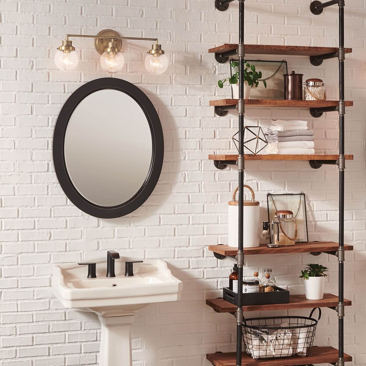 Vue en situation d'une applique au-dessus d'un lavabo et miroir ovale, mur en briques.