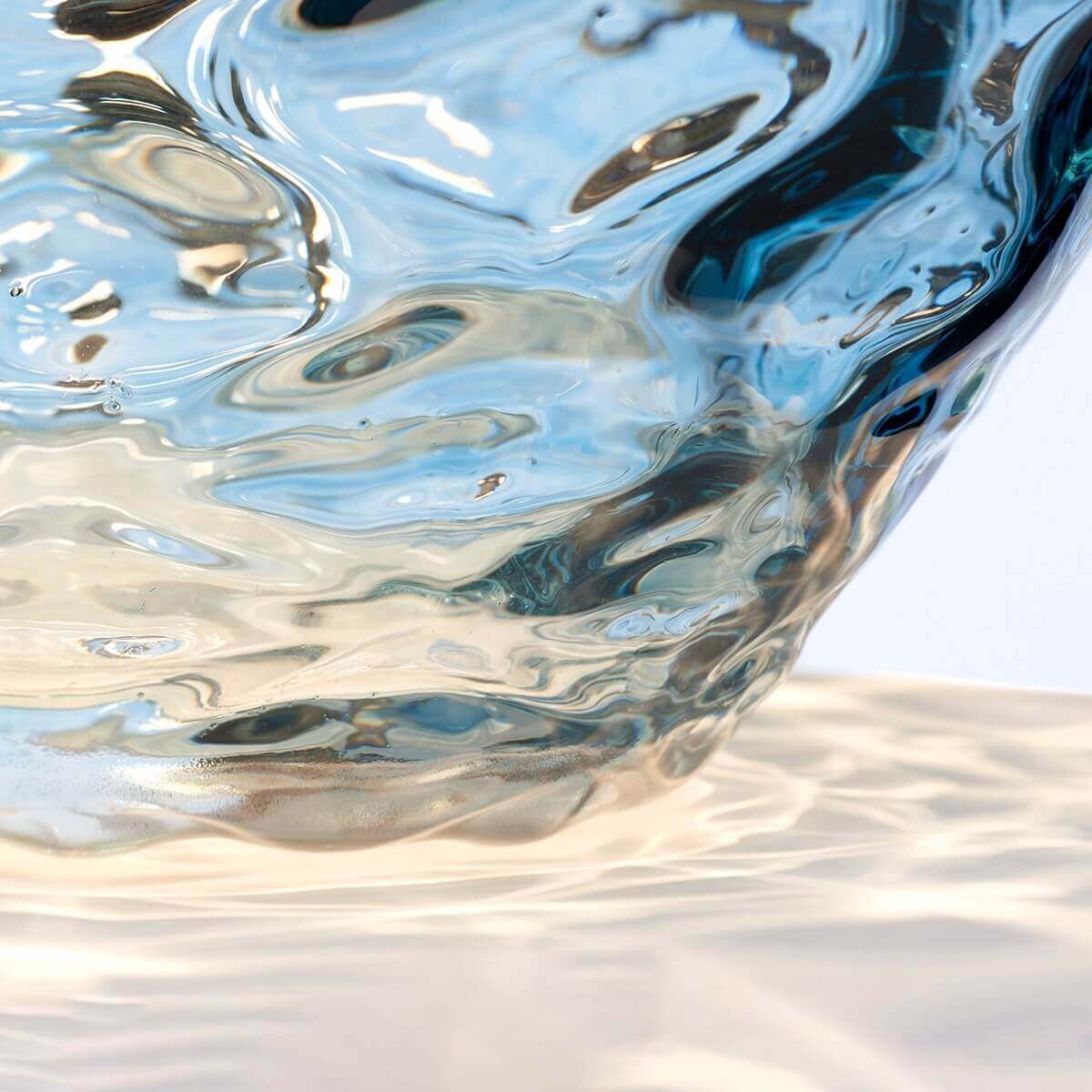 Détail rapproché du verre soufflé aux reliefs ondulés et reflets bleutés