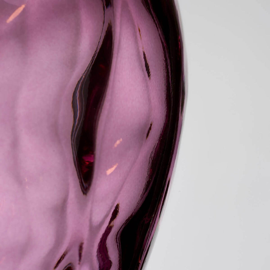 Gros plan sur la texture du verre rose, motifs martelés et reflets translucides