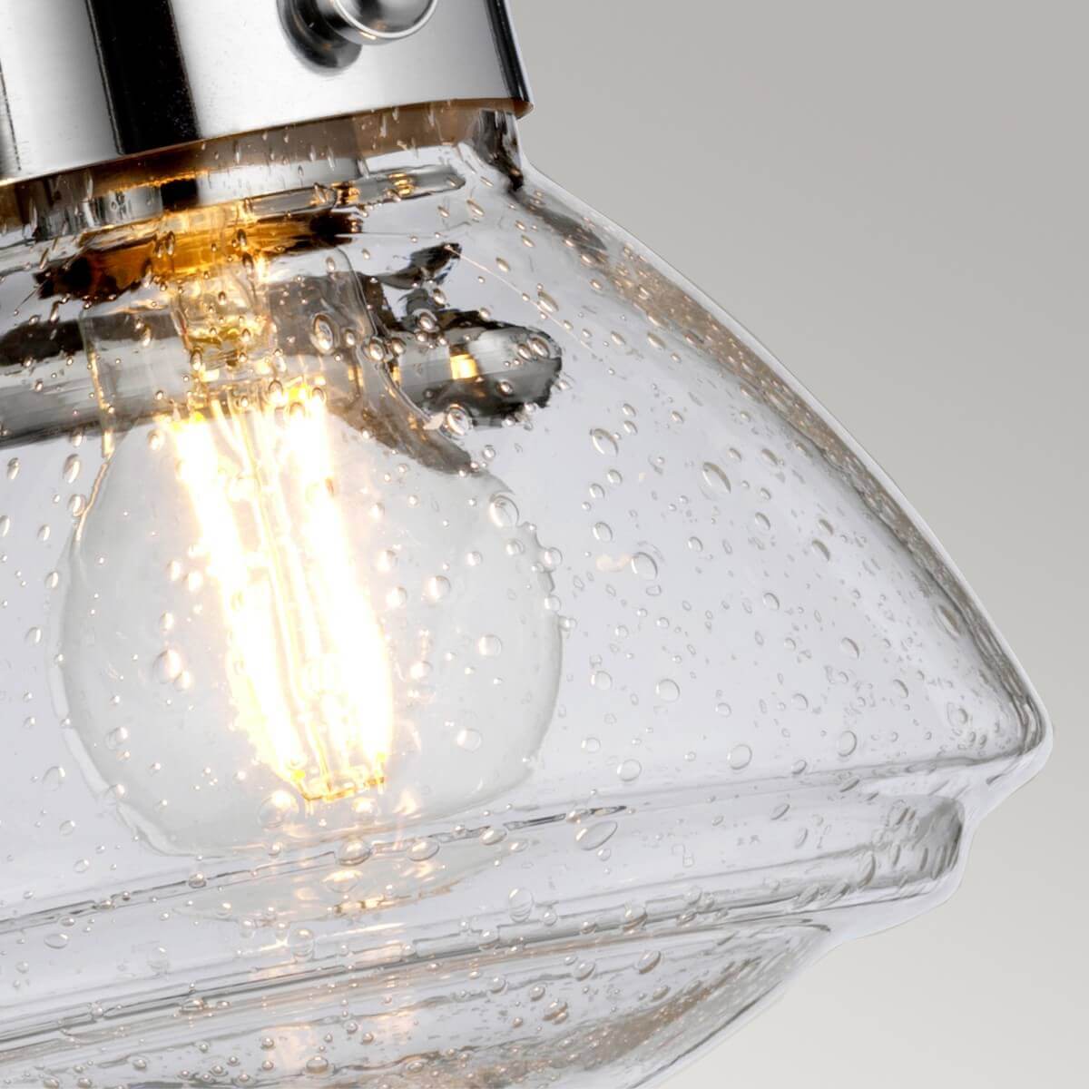 Détail rapproché du verre bullé et du filament incandescent de l'ampoule allumée