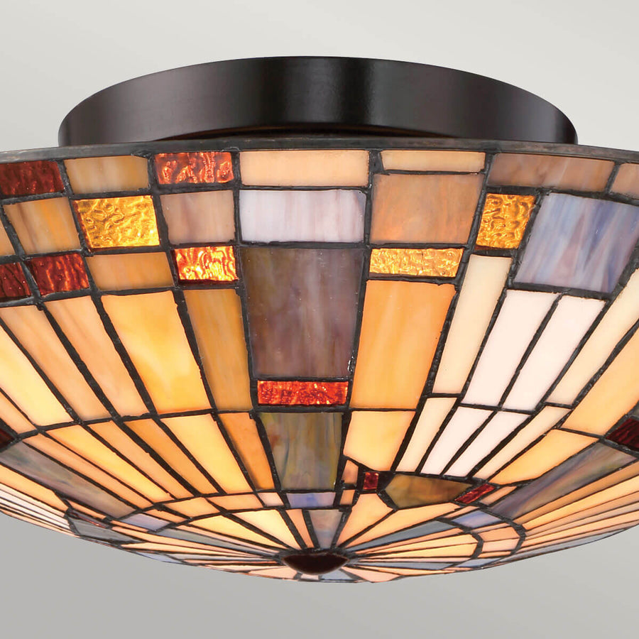 Gros plan sur le verre mosaïque et la couronne métallique brun foncé du luminaire
