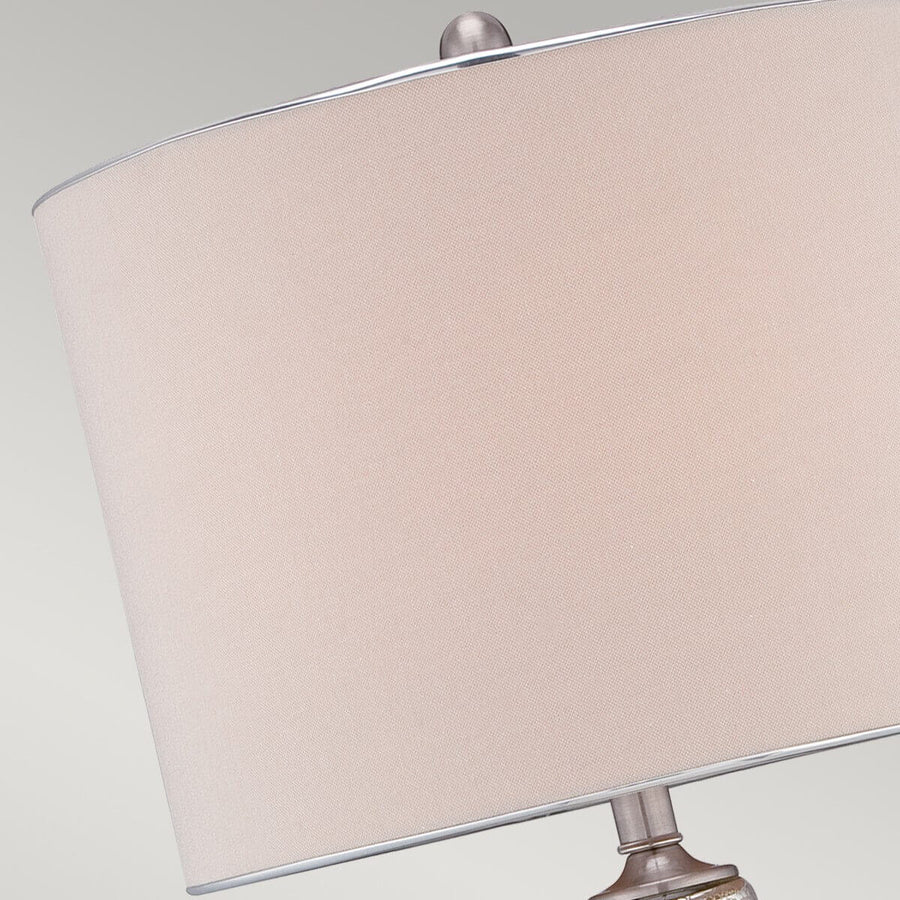 Gros plan sur l'abat-jour beige, son passepoil clair et le bouton de fixation