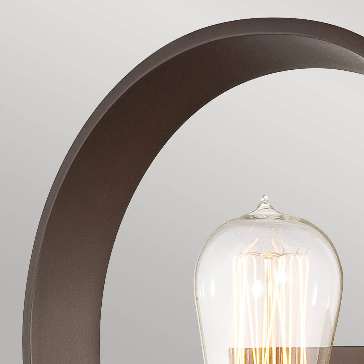 Détail du cercle en métal bronze et du sommet de l'ampoule transparente allumée