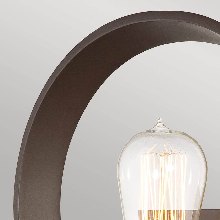 Détail du cercle en métal bronze et du sommet de l'ampoule transparente allumée