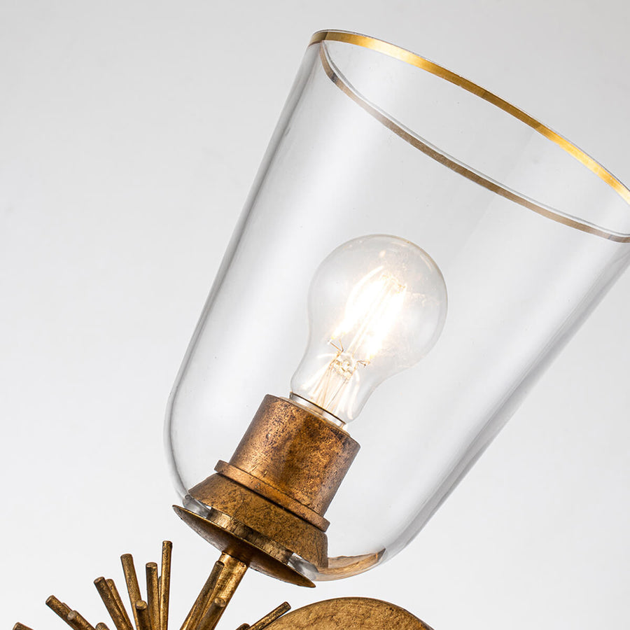 Gros plan sur l'abat-jour en verre transparent, liseré doré et ampoule allumée