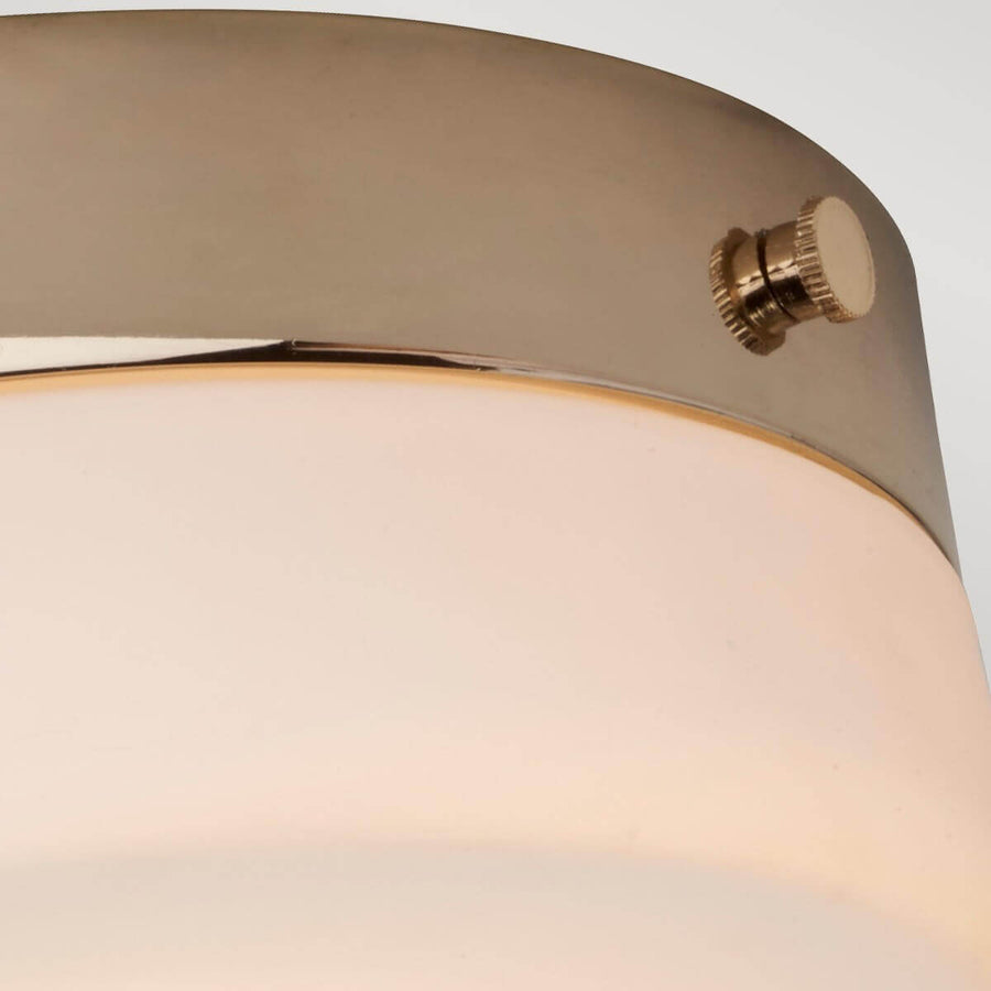 Détail de la finition dorée et vis moletée sur le bord du luminaire.