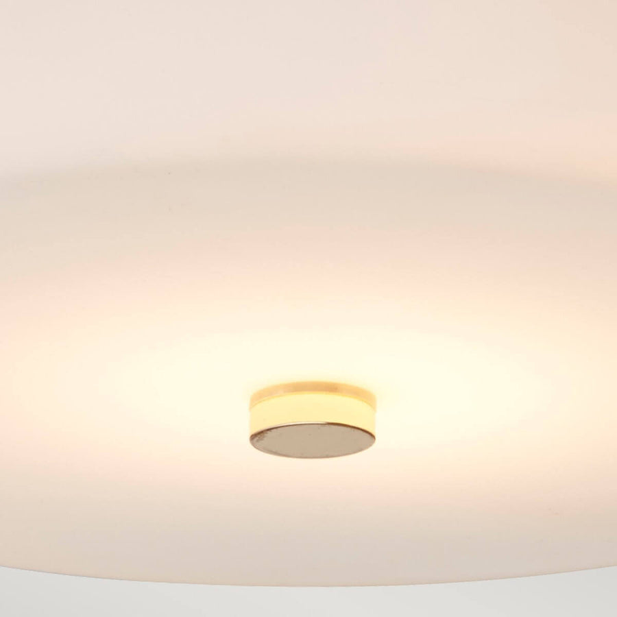 Vue par-dessous montrant le diffuseur en verre blanc et le cabochon central doré.