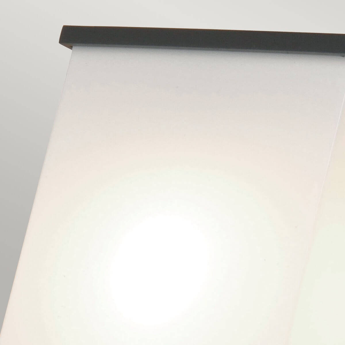 Détail rapproché du bord supérieur, cadre métallique sombre sur verre opalin