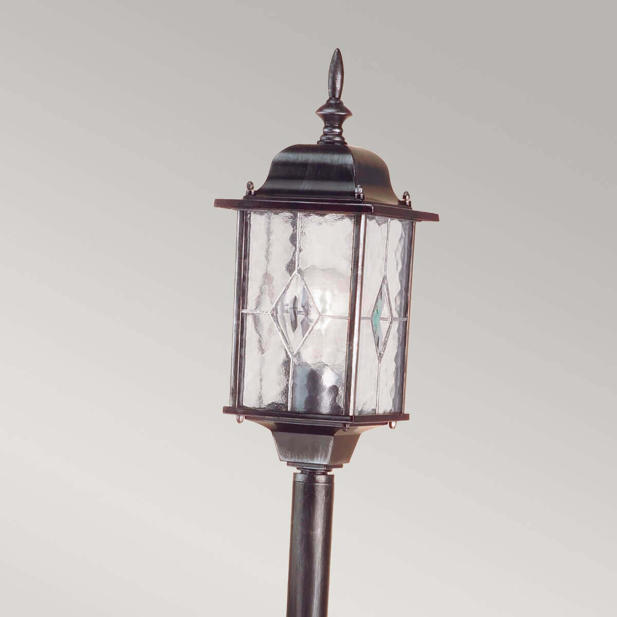Gros plan sur la lanterne en verre ornée de losanges et sa pointe décorative.