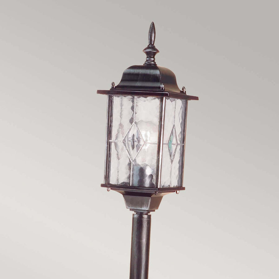 Gros plan sur la lanterne en verre ornée de losanges et sa pointe décorative.