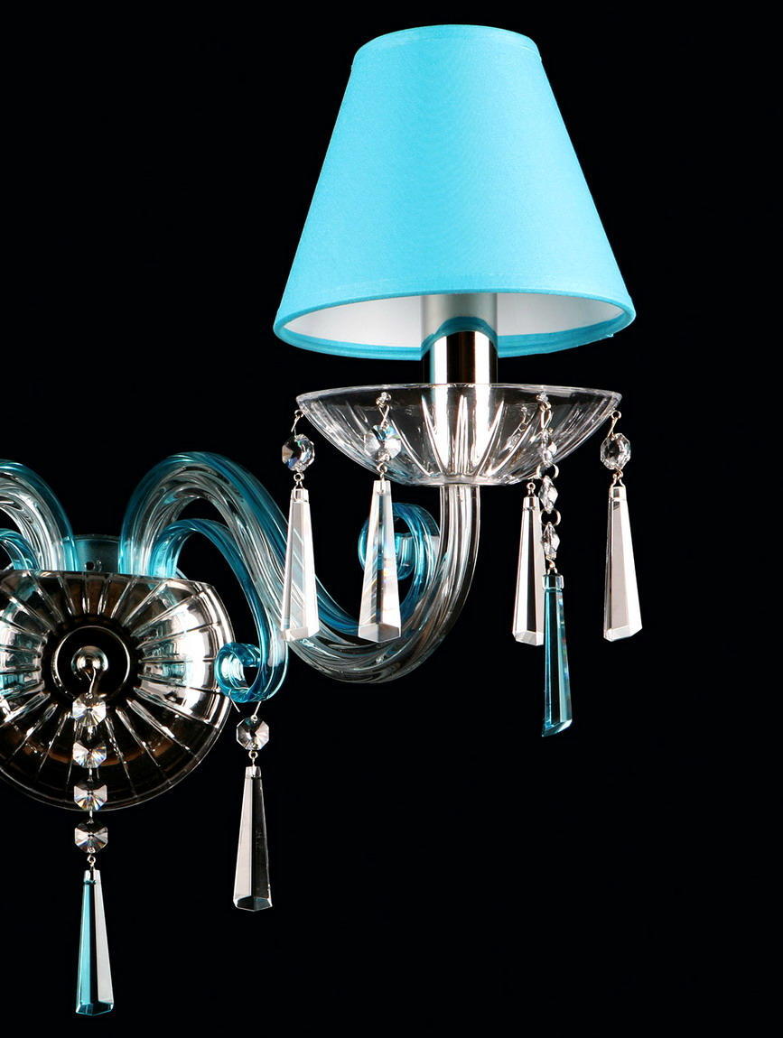 Gros plan sur un bras, abat-jour bleu, coupe en verre et pampilles transparentes