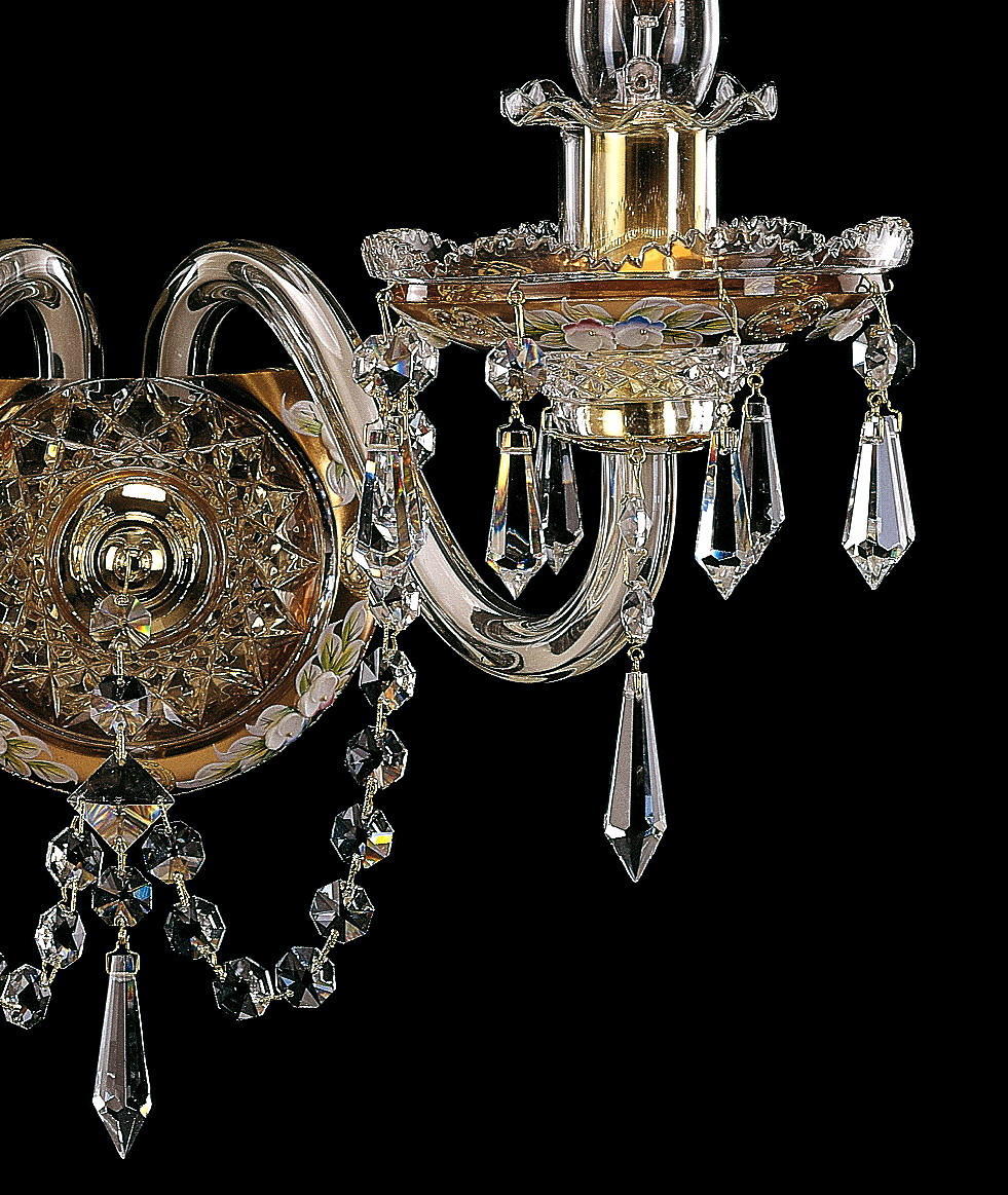 Détail rapproché d'une coupelle ciselée, guirlandes de cristal et bras recourbé doré.