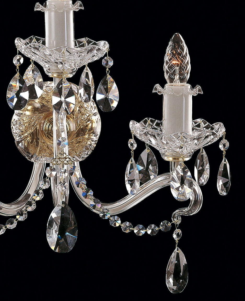 Gros plan sur un bras recourbé, coupelle ciselée et pendentifs en cristal taillé suspendus.