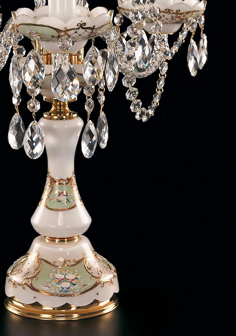 Gros plan du pied en porcelaine peinte de fleurs, dorures et grappes de cristal suspendues