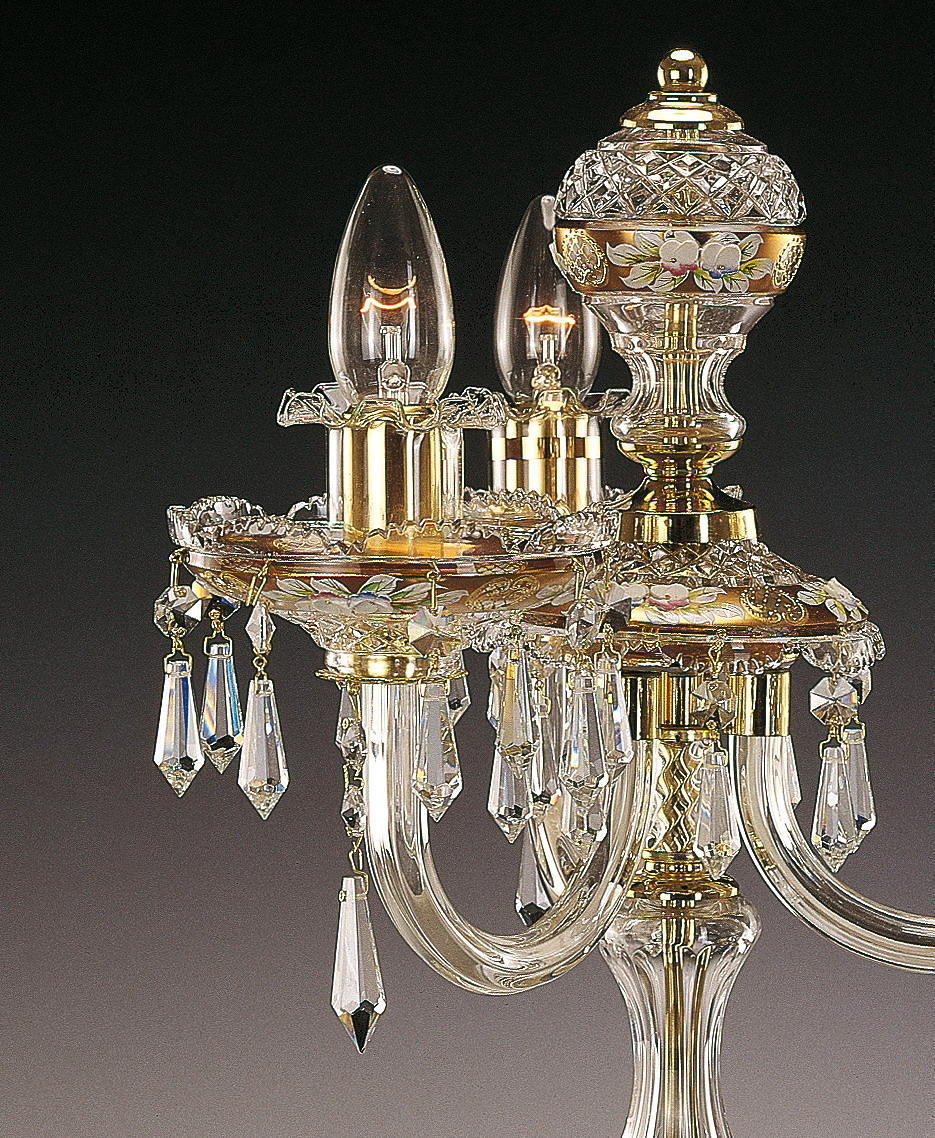 Détail du sommet avec douilles dorées, ampoules allumées, pendentifs en cristal et frise florale émaillée.