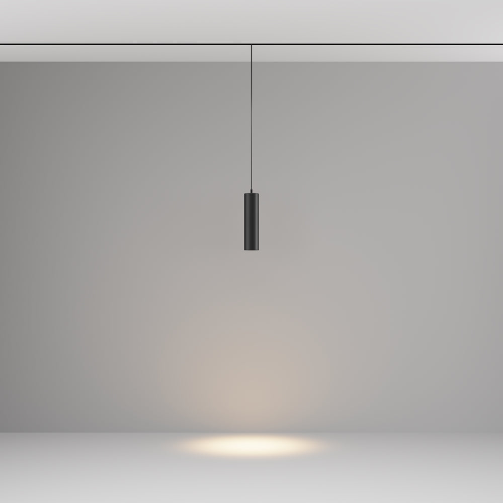 Cylindre noir allumé projetant un halo de lumière chaude sur le sol, fond neutre.