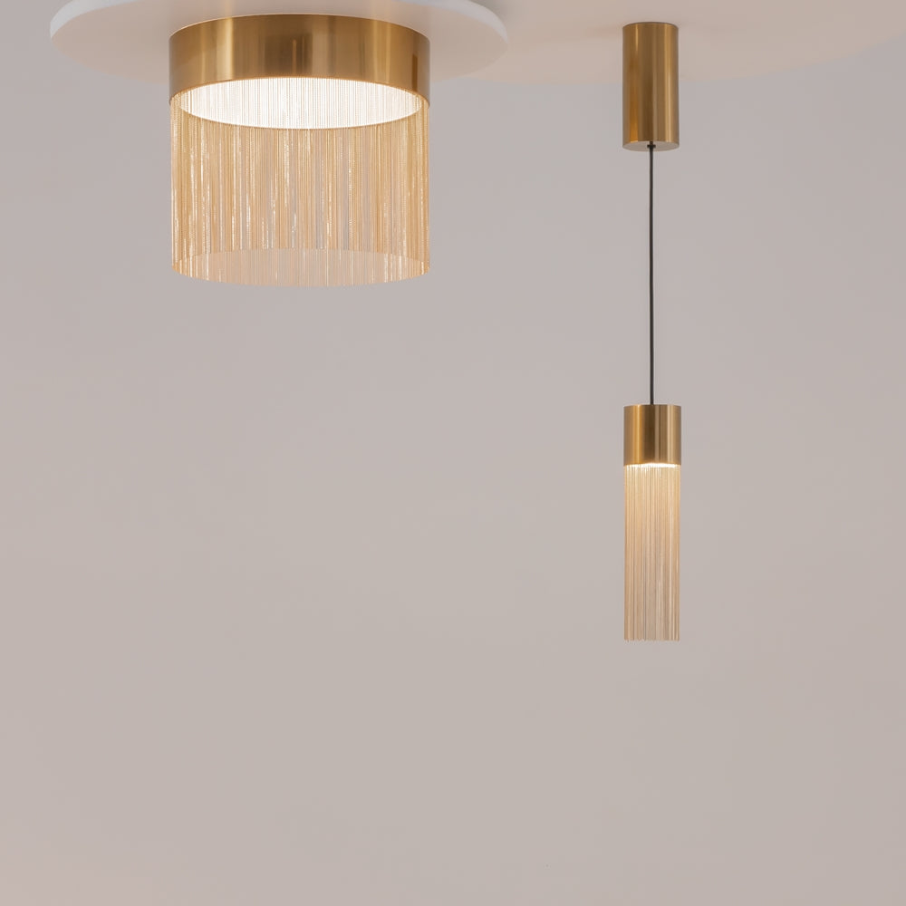 Deux luminaires dorés côte à côte, un grand format rond et une suspension étroite