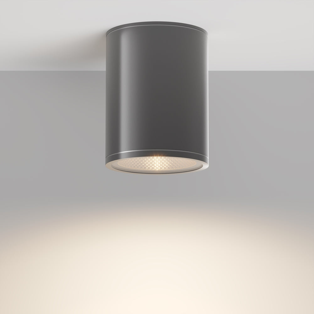 Luminaire gris vu de trois quarts sous plafond, lumière chaude projetée