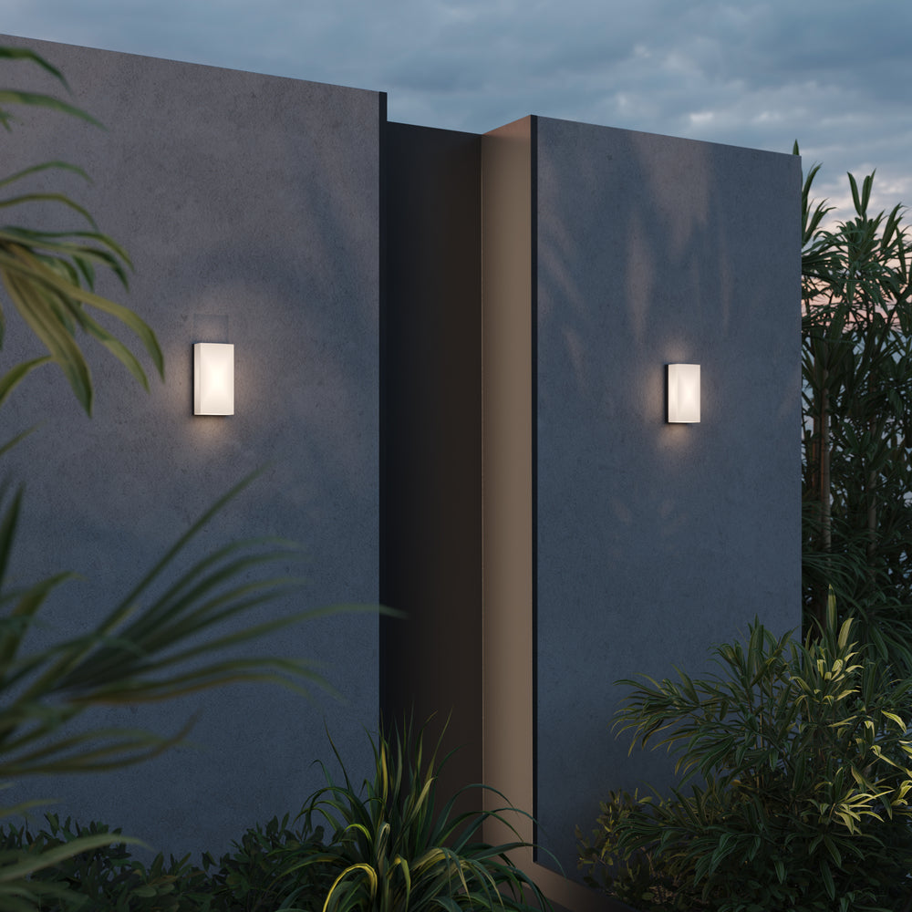 Mise en ambiance nocturne extérieure, deux appliques éclairant une façade et des plantes