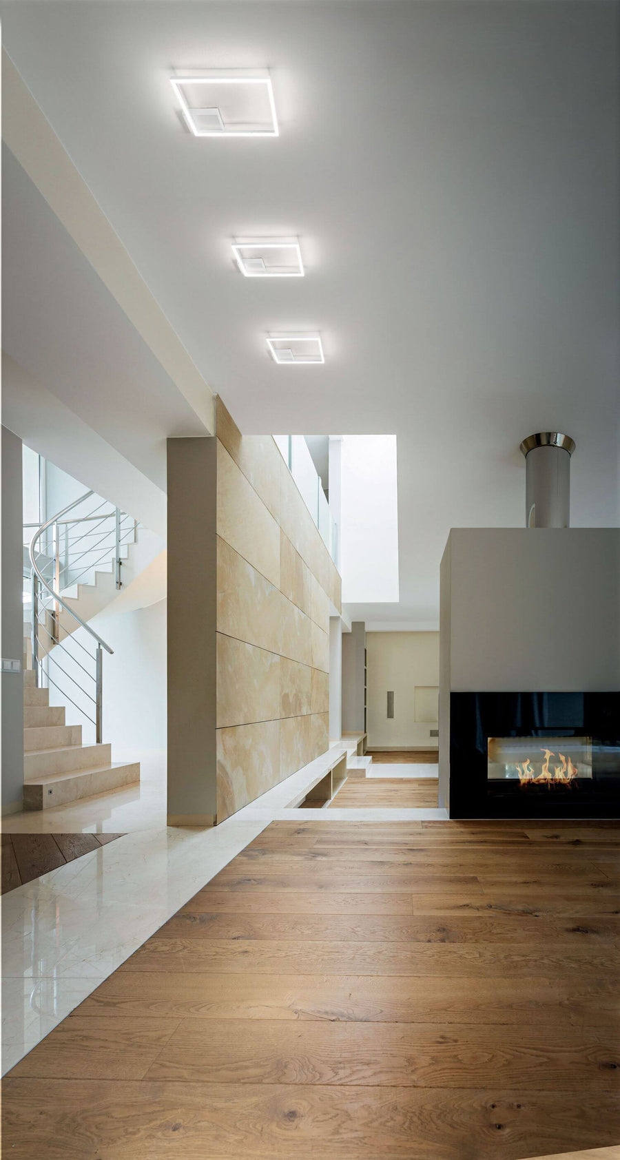 Le plafonnier blanc installé au plafond d'une grande pièce à cheminée et escalier
