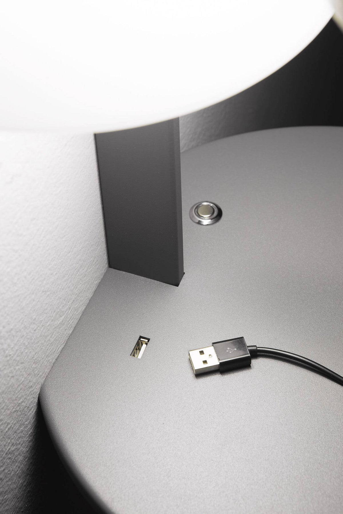 Détail du plateau gris avec bouton tactile, port USB et connecteur USB débranché à proximité