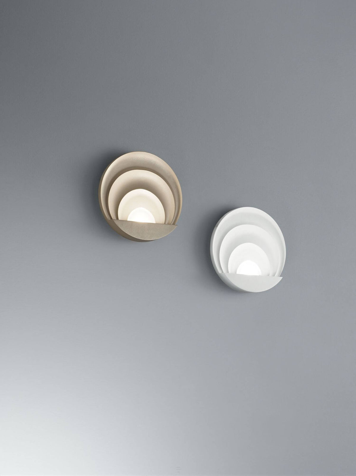 Deux appliques murales comparées sur mur gris, une beige sable et une blanche