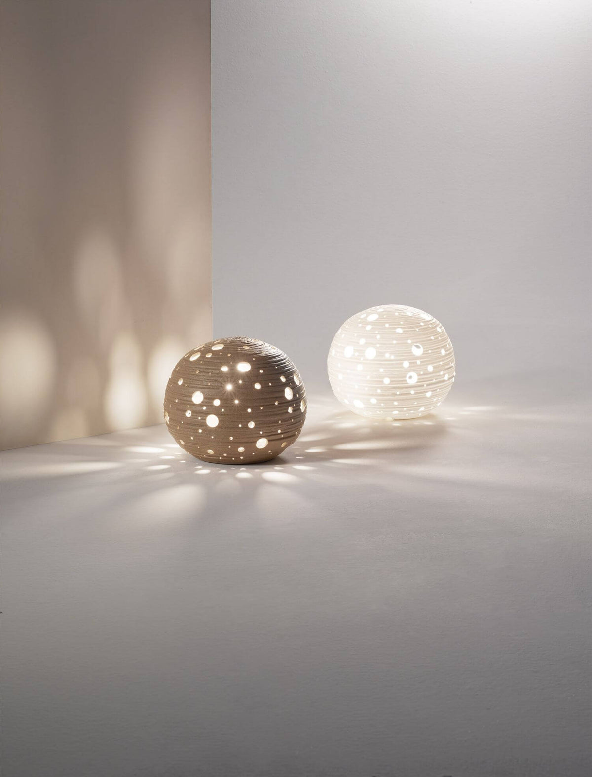 Détail de deux globes perforés éclairés projetant des points lumineux sur le sol