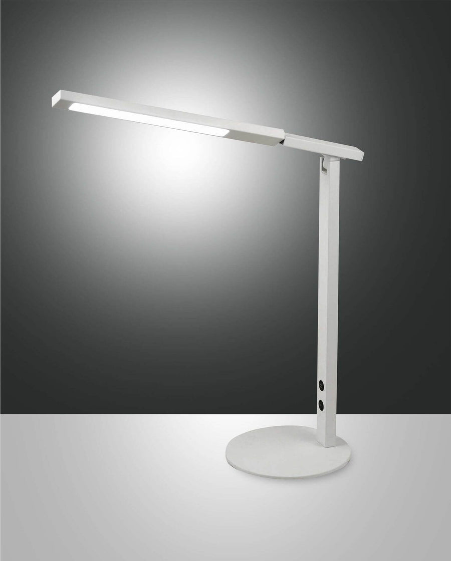 Lampe de bureau blanche de face sur fond gris, bras incliné et lumière allumée