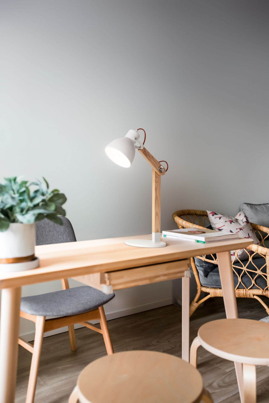 Lampe à poser allumée sur un bureau en bois, dans un intérieur scandinave
