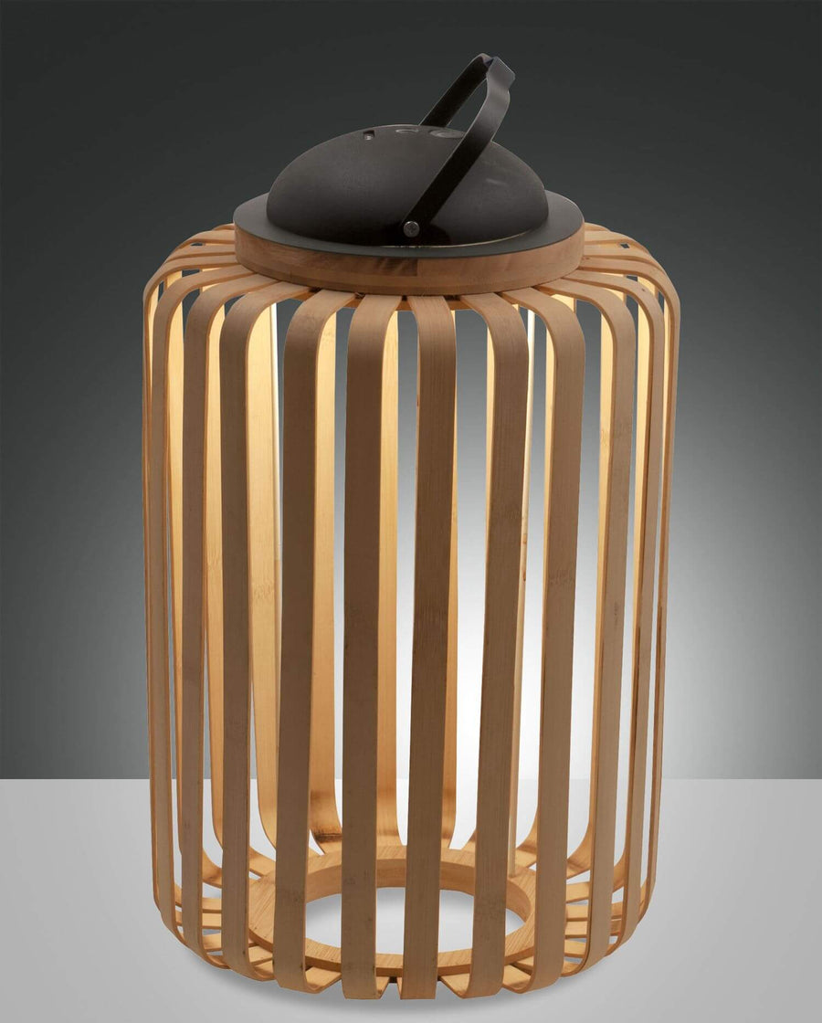 Lampe cylindrique en bois ajouré avec poignée noire, vue de face sur fond gris.