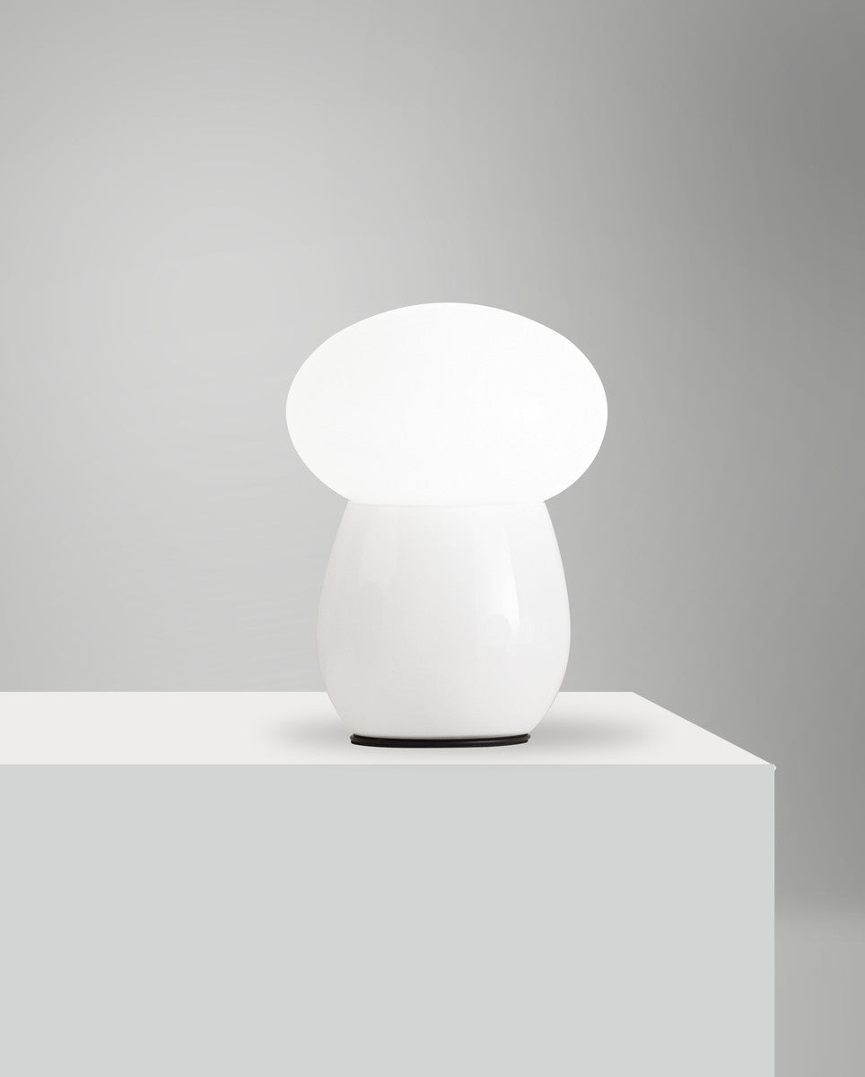 Lampe blanche allumée posée sur un socle, vue de face en hauteur